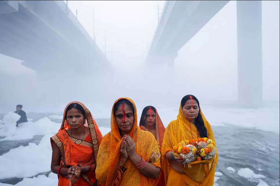 Индуистские верующие поклоняются богу Солнца, стоя на берегу загрязненной реки Ямуна во время индуистского религиозного праздника Чхатх Пуджа в Нью-Дели, Индия, 19 ноября 2023 года. Фото: Reuters