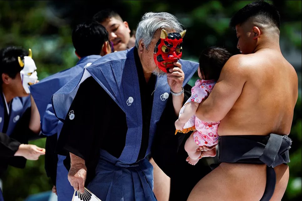 Помощники судьи одевают маски, чтобы напугать младенцев во время фестиваля наки сумо в храме Сенсо-Ди в Токио, Япония, 28 апреля 2024 года. Фото: Reuters