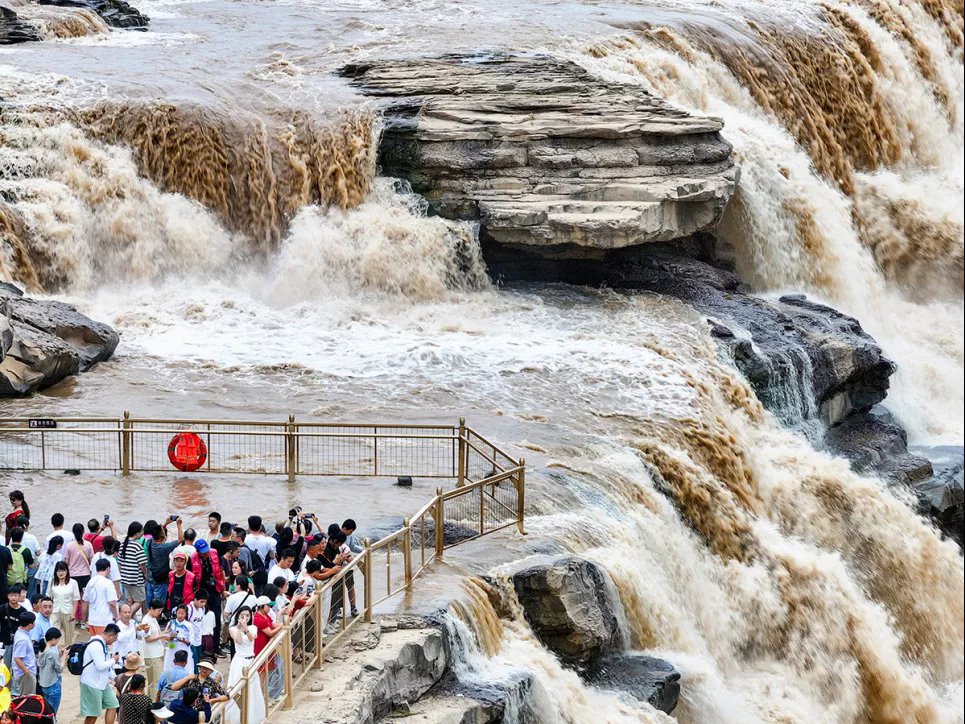 Туристы наблюдают за усилившимся потоком воды в водопаде Хукоу на реке Хуанхэ возле города Линфэн, китайская провинция Шаньси, 15 августа 2024 года. Фото: Reuters