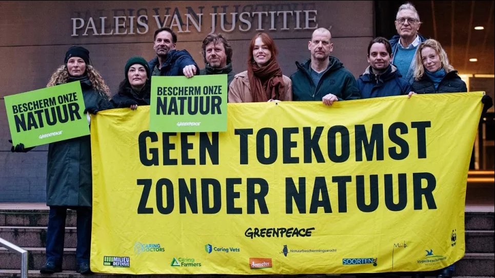 Сотрудники Greenpeace перед Дворцом правосудия в Гааге с плакатом «Нет будущего без природы» и зелеными табличками с надписью «Защитите нашу природу». Скриншот видео от Marten van Dijl