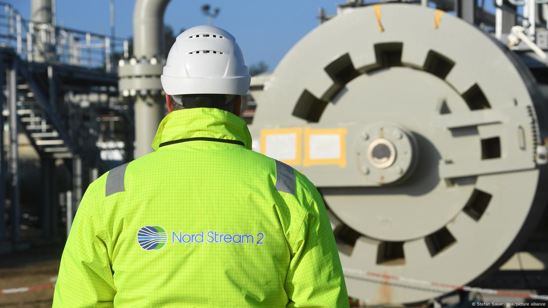 Чоловік в уніформі з написом Nord Stream 2 на спині на тлі компресорної станції у Лубміні. Фото: Stefan Sauer/dpa/picture alliance