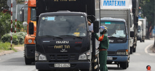 Військовий офіцер перевіряє проїзні документи вантажівки на блокпості Covid-19 у Хошиміні. Фото VnExpress/Quynh Tran