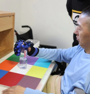 Перший пацієнт, який отримав систему інтерфейсу мозкового чипа NEO, здатний хапати предмети за допомогою протеза руки. Фото: Університет Цінхуа