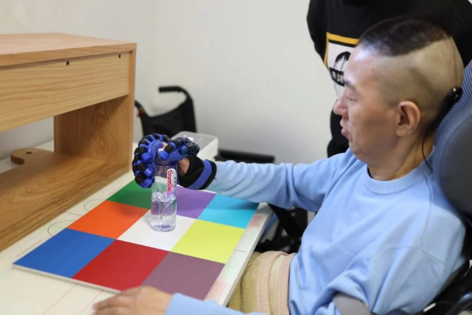 Перший пацієнт, який отримав систему інтерфейсу мозкового чипа NEO, здатний хапати предмети за допомогою протеза руки. Фото: Університет Цінхуа