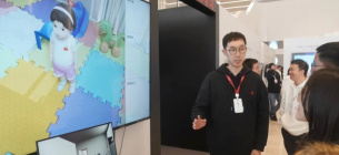Исследователь из Пекинского института всеобщего искусственного интеллекта объясняет, как взаимодействовать с Тонг Тонгом на выставке Frontiers of General Artificial Intelligence Technology Exhibition в Пекине в конце января. Фото: bjd.com