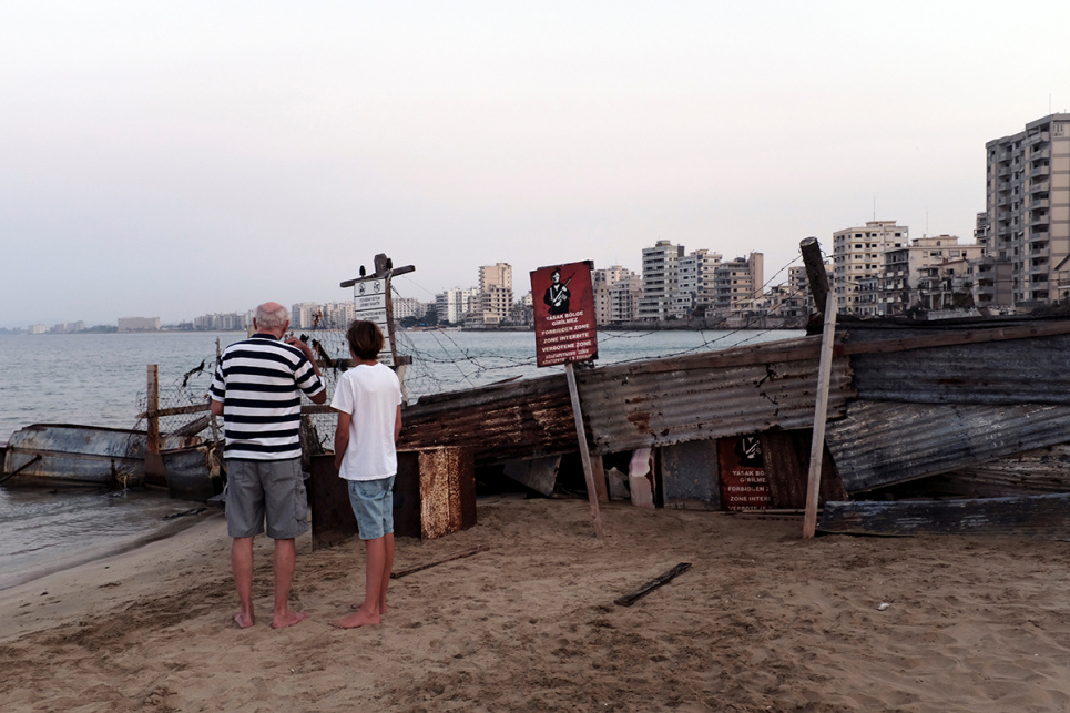 Люди дивляться на покинутий район Вароша — територію, окуповану турецькими військовими з часів розділу Кіпру у 1974 році — під час прогулянки пляжем у Фамагусті, Кіпр, 5 серпня 2019 року. Фото: Reuters