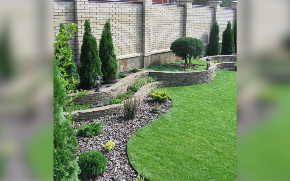 Піднесена клумба з оздобленням із природного каменю та строгий цегляний паркан — креативні ідеї Фото з відкритих джерел